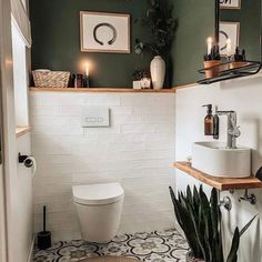 a white toilet sitting in a bathroom next to a sink under a mirror and potted plant