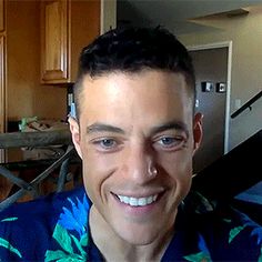 a man in a hawaiian shirt smiling at the camera