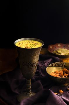 there is a bowl of food next to a wine glass on a purple table cloth