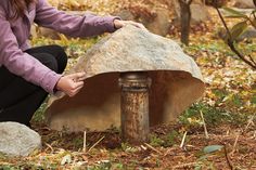 a woman kneeling down next to a large rock