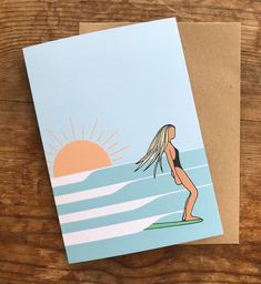 a greeting card featuring a woman standing on a surfboard