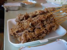 skewers of meat are on a plate with other food items in the background