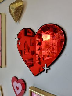 a heart shaped mirror mounted to the side of a wall next to other framed pictures