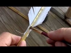 a person holding a feather on top of a wooden table