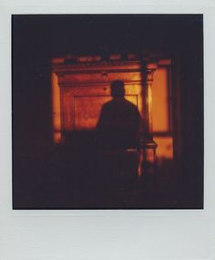 a man sitting in front of a window with his shadow on the wall