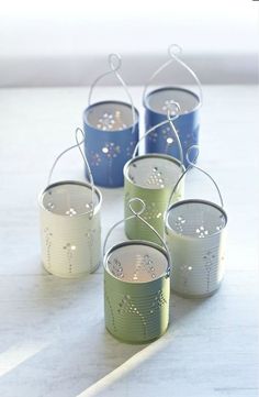 four small tin canisters sitting on top of a table with the words pretty diy lanterns