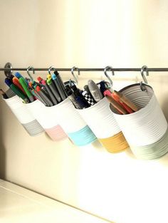 several cups are hanging on a rack with pens and pencils in them to dry off