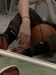 a person sitting on the floor with a basketball in front of them and their reflection