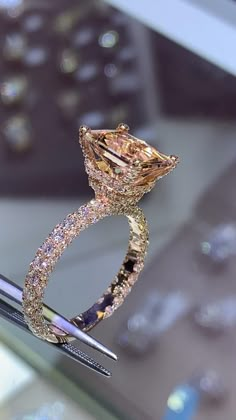 a diamond ring is being held up by a pen