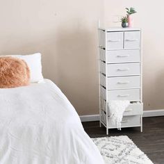 a white bed sitting next to a tall white dresser on top of a hard wood floor