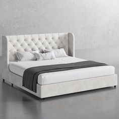 a bed that is made up with white sheets and pillows on top of the headboard