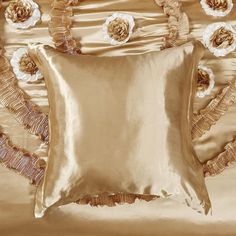 a gold pillow with ruffled edges on a satin bed sheet and matching decorative wall hangings