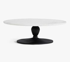 a white table with black legs and a round marble top on an oval base, viewed from the front