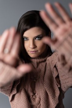 a woman with her hands out in front of her face and looking at the camera