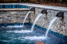 three fountains are running from the side of a swimming pool