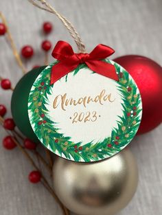 a christmas ornament with a red bow on it next to ornaments and berries