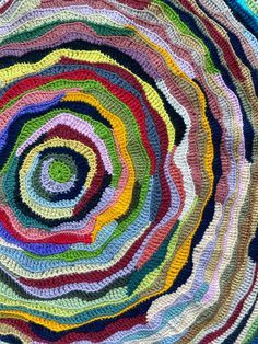 a multicolored crocheted rug is shown in the shape of a spiral