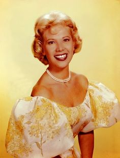 an old photo of a woman in a yellow and white dress with pearls on her necklace