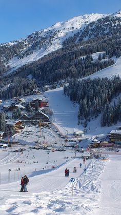 a ski resort with people skiing and snowboarding on the slopes in front of it