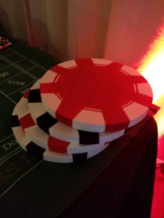 three red and white poker chips sitting on top of a table next to a neon light