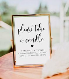 a sign that says please take a candle on it next to a wooden table with white feathers