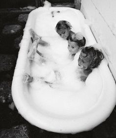 three children are sitting in the bathtub together