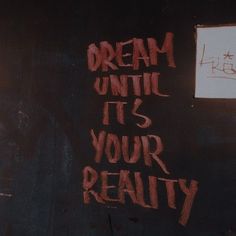 graffiti on the side of a building reads, dream until it's your reality