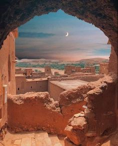 an arch in the side of a building that has a moon above it and some rocks below