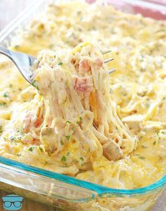 a fork full of food in a casserole dish with meat and cheese on top