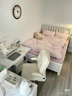 a small bedroom with a bed, desk and chair in front of a clock on the wall