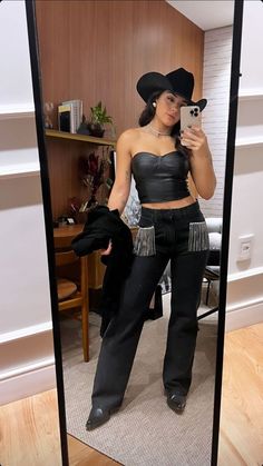 a woman taking a selfie in a mirror wearing black pants and a crop top