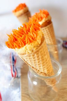 two ice cream cones with orange icing on them