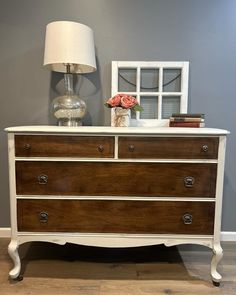 a white dresser with two drawers and a lamp on top