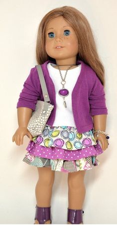 the doll is wearing a purple cardigan and skirt