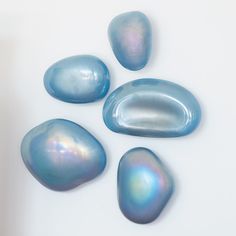 four blue and white rocks on a white surface with one rock in the foreground