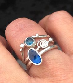 a woman's hand holding a ring with blue stones