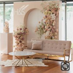 a living room with flowers on the wall and furniture in front of large glass windows