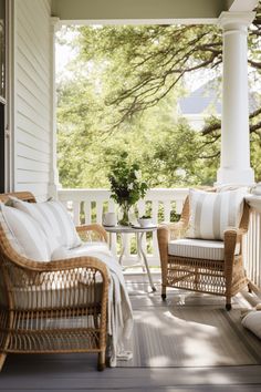 two wicker chairs sitting on a porch next to a table with a plant in it