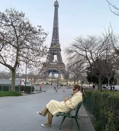 a woman sitting on a bench in front of the eiffel tower