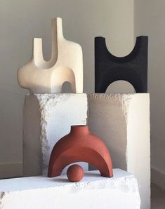 three vases sitting on top of each other in front of a white wall and floor