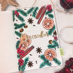 an open notebook with the word december written on it next to christmas decorations and baubles