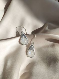 Small delicate wire-wrapped earrings are made of genuine white moonstone with lovely floating sheen from both sides. The ear wire hook is made of sterling silver 925, it is perfect for sensitive ears. It is nice dainty jewelry for every occasion and will fit every outfit. The earrings are lightweight because of the aluminum wire wrapping, and have stunning sparkles of blue color on the stones! MOONSTONE is the stone of feminine energy, spirituality, connection with the inner goddess, self-love, and revealing inner peace and harmony. The stone works with a crown chakra, and it is a June birthstone. . 🔶MATERIALS: Stones: moonstone. Stones diameter: 10mm. Ear wire: sterling silver 925. Other elements: aluminum wire, non-tarnish, hypoallergenic. Length: 3.5cm / 1.37in 🔶Matching pendants to m Fairy Stone, Cool Earrings, White Beaded Necklaces, Boho Fairy, Wrapped Earrings, Witchy Jewelry, Wire Wrapping Stones, White Moonstone, Le Crochet