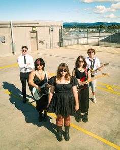 a group of people standing on top of a parking lot with guitars in their hands