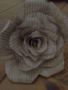 a flower made out of book pages sitting on top of a wooden table