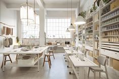 a room filled with lots of white tables and chairs next to shelves full of items