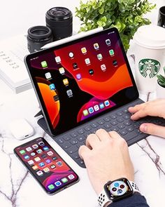 a person sitting at a table with an apple laptop and cell phone on their lap