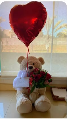 a teddy bear holding a heart shaped balloon with flowers and a tag attached to it