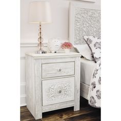 a bedroom with a bed, nightstand and lamp on the night stand in front of it