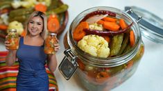 a woman holding two jars filled with vegetables