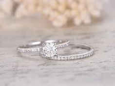 two white gold engagement rings with diamonds on the side and one diamond in the middle